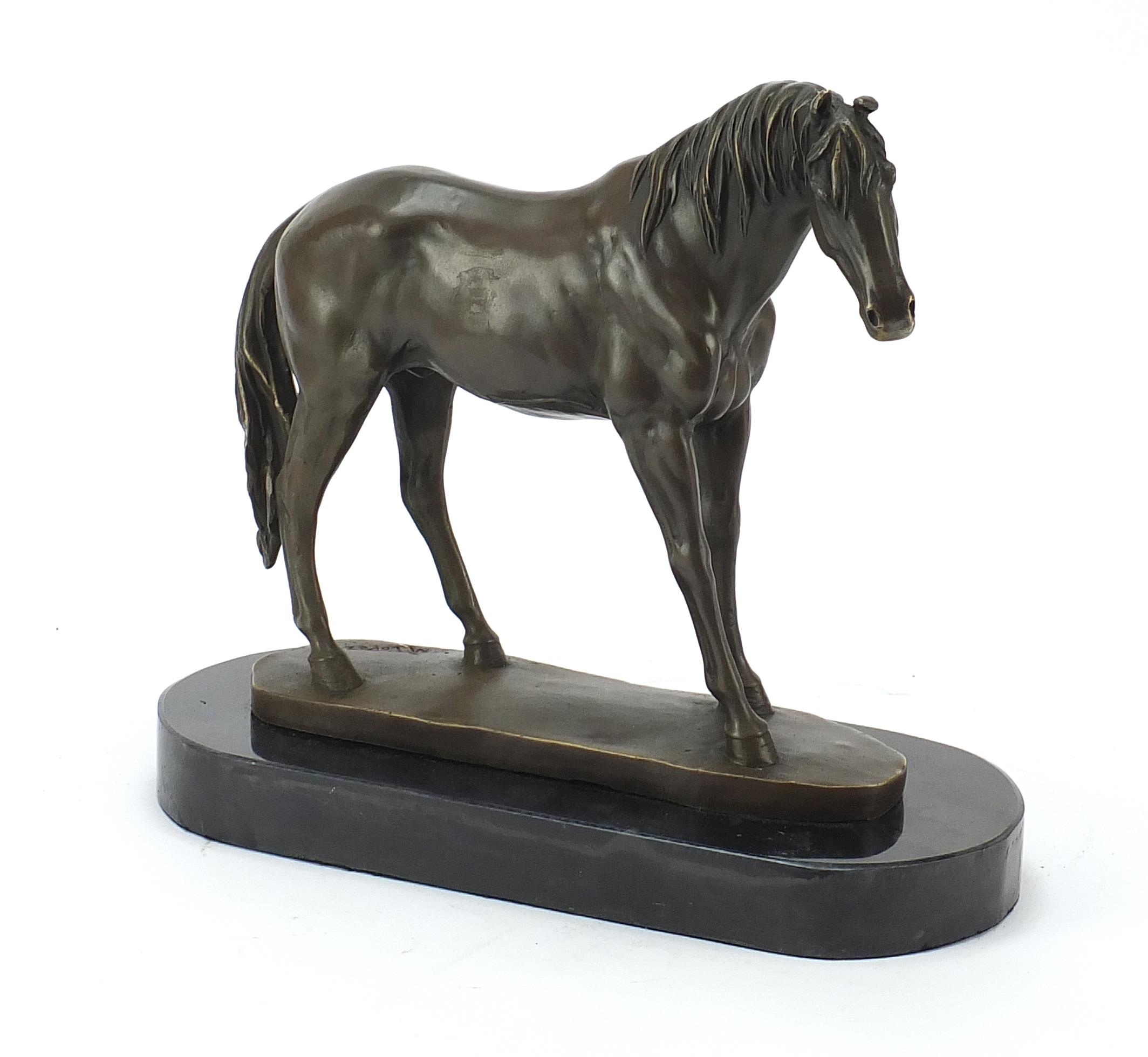Patinated bronze horse raised on a black slate base, 33cm in length