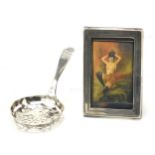 Antique continental silver sifting spoon and a miniature rectangular silver easel photo frame, the