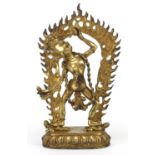 Chino Tibetan gilt devil figure standing on two people, 30cm high