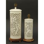 Two Chinese porcelain blanc de chine pierced table lamps raised on carved hardwood bases, the