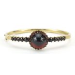 Antique gilt metal garnet hinged bangle, the clasp impressed Amerikaner, 7cm wide, 14.4g