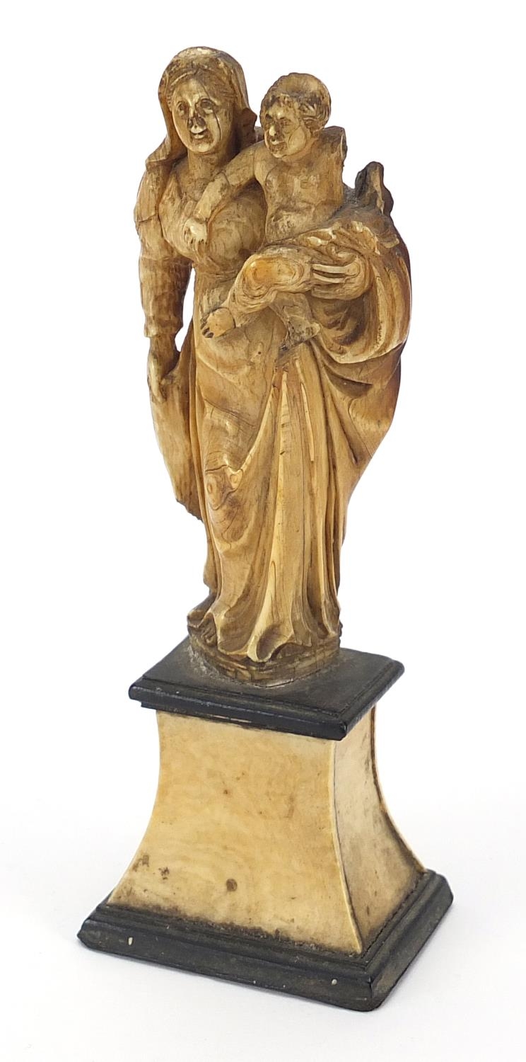 Antique ivory carving of Madonna and child raised on an ebonised and ivory base, 14cm high