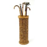 Six wooden walking sticks and a wicker stick stand including one with bronzed putti handle and one