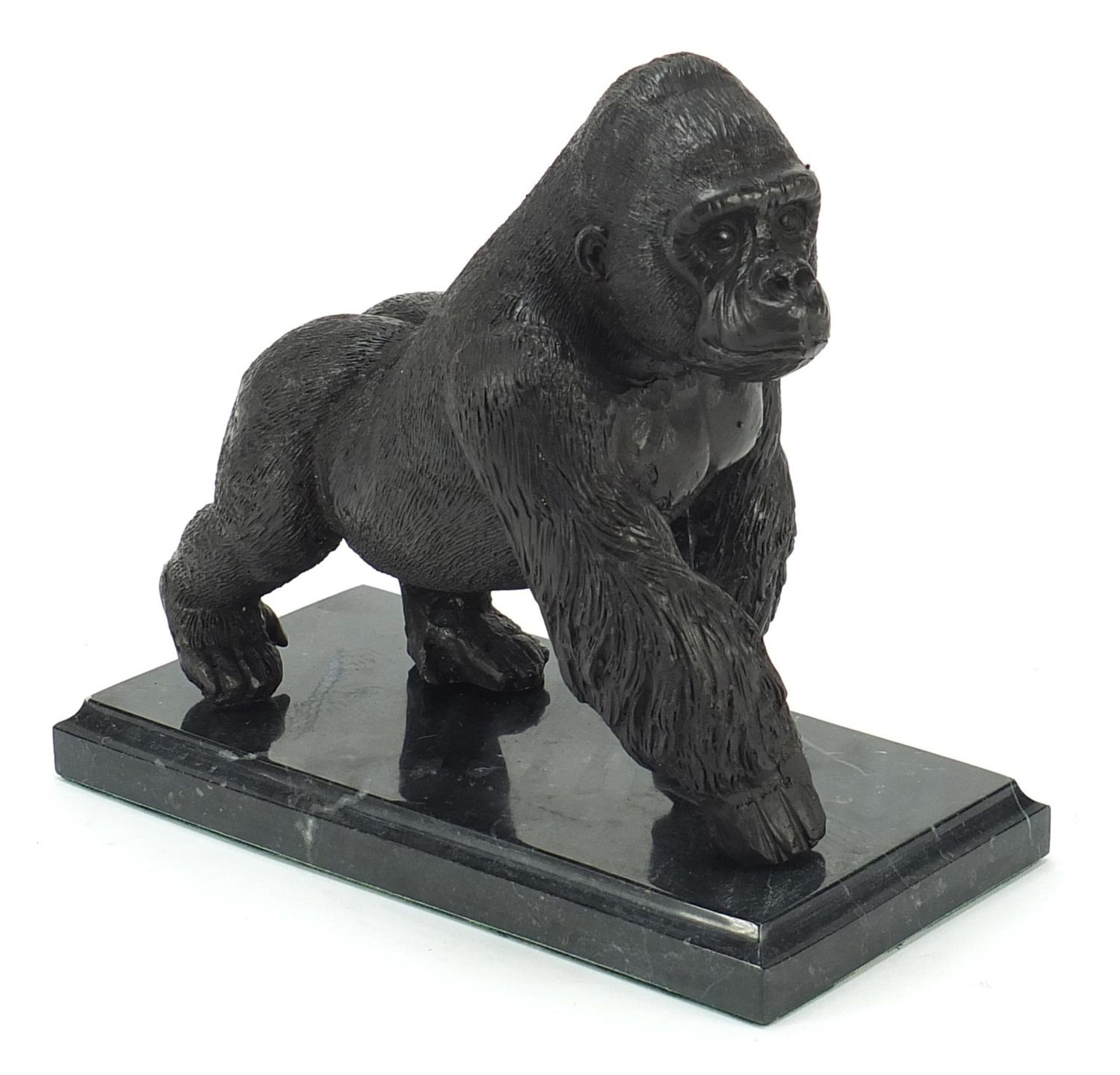 Patinated bronze gorilla raised on a black marble base, 20cm in length