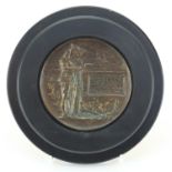 Military interest bronzed plaque with ebonised frame, 13cm in diameter