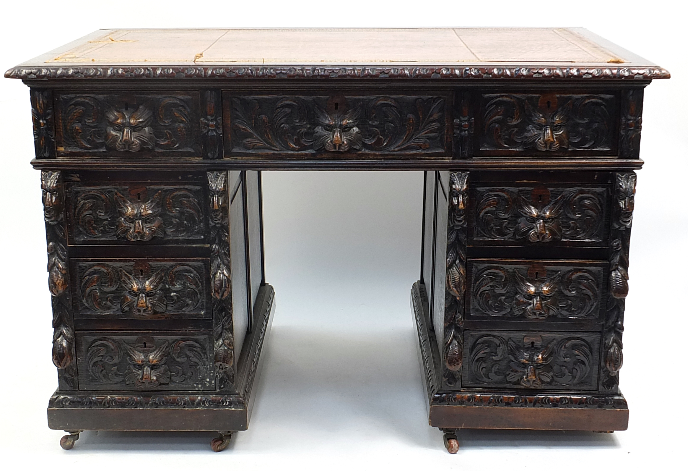 Oak twin pedestal desk with tooled leather top above a series of drawers, carved with lions heads,