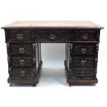 Oak twin pedestal desk with tooled leather top above a series of drawers, carved with lions heads,