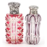 Two Victorian cranberry and amethyst flashed cut glass scent bottles with silver lids, the largest