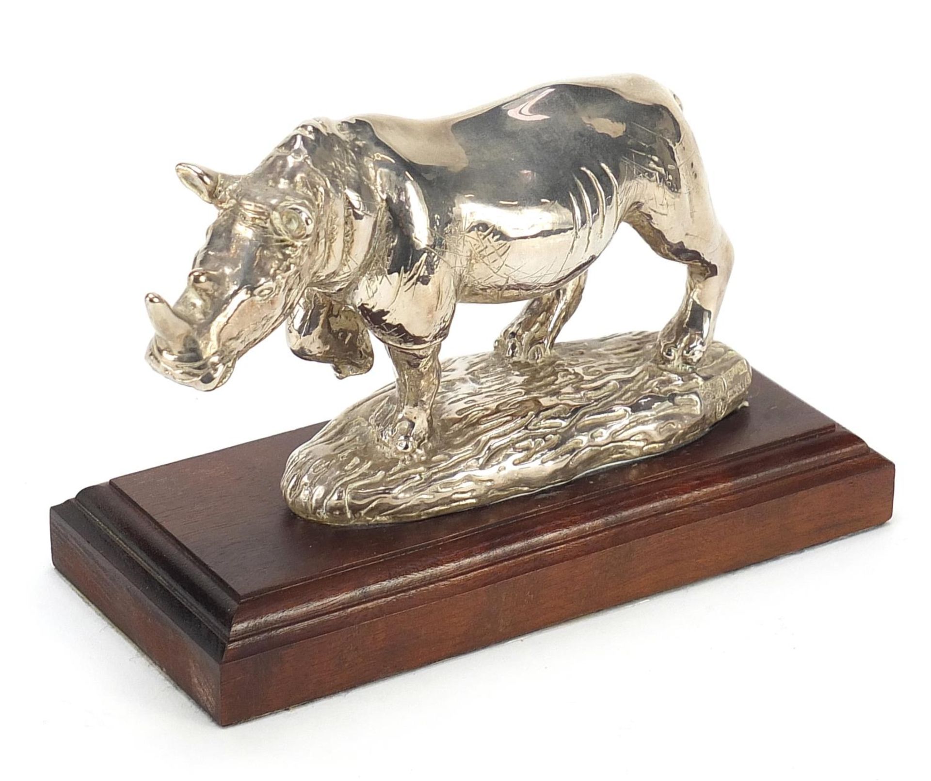 Afrisilver, African sterling silver filled rhinoceros, raised on a wooden base, 16cm in length