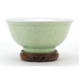 Chinese porcelain bowl raised on hardwood stand having a celadon glaze, decorated in relief with