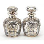 Pair of unmarked silver overlaid glass scent bottles pierced with flowers, 11.5cm high