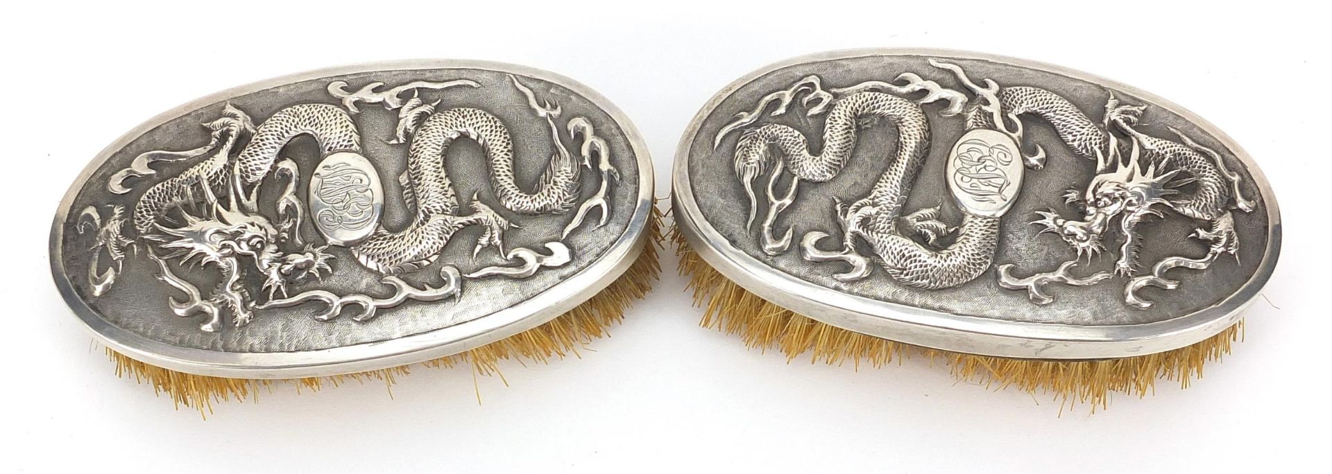 Pair of Chinese silver backed brushes embossed with dragons by Woshing, 13cm wide