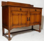 1930S OAK SIDEBOARD WITH CARVED PANELS AND BRASS SWING HANDLES.