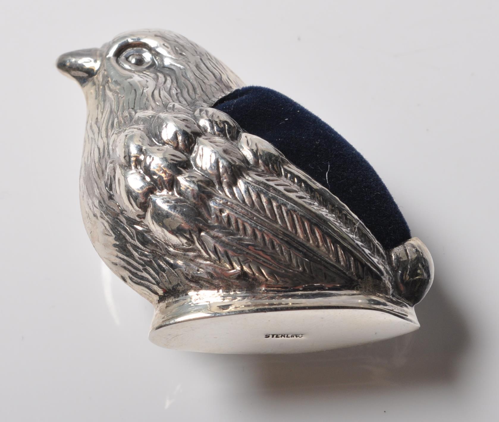 A STAMPED STERLING SILVER PINCUSHION IN THE FORM OF A ROBIN