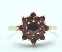 9CT GOLD HALLMARKED CLUSTER RING WITH RED STONES.