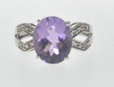 HALLMARKED 9CT WHITE GOLD AND PURPLE STONE RING.