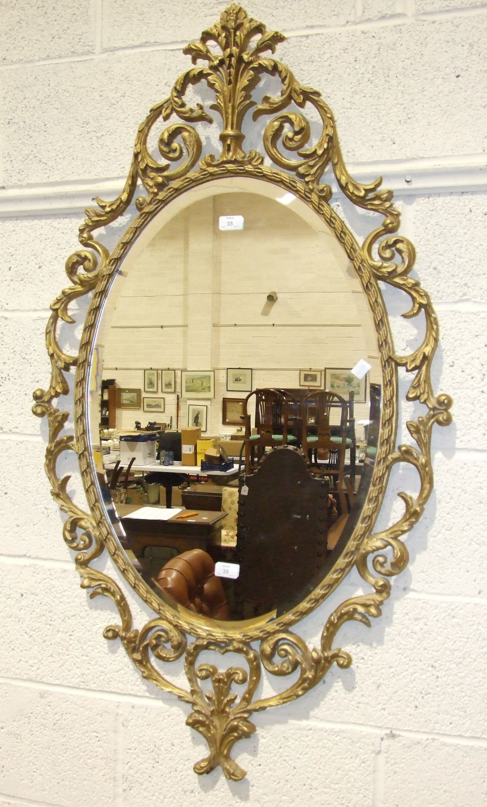 A modern gilt metal bevel-edged oval wall mirror with foliate surround, 127 x 70cm overall.