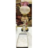 A brass and ceramic oil lamp, the ceramic reservoir with raised floral decoration on brass base