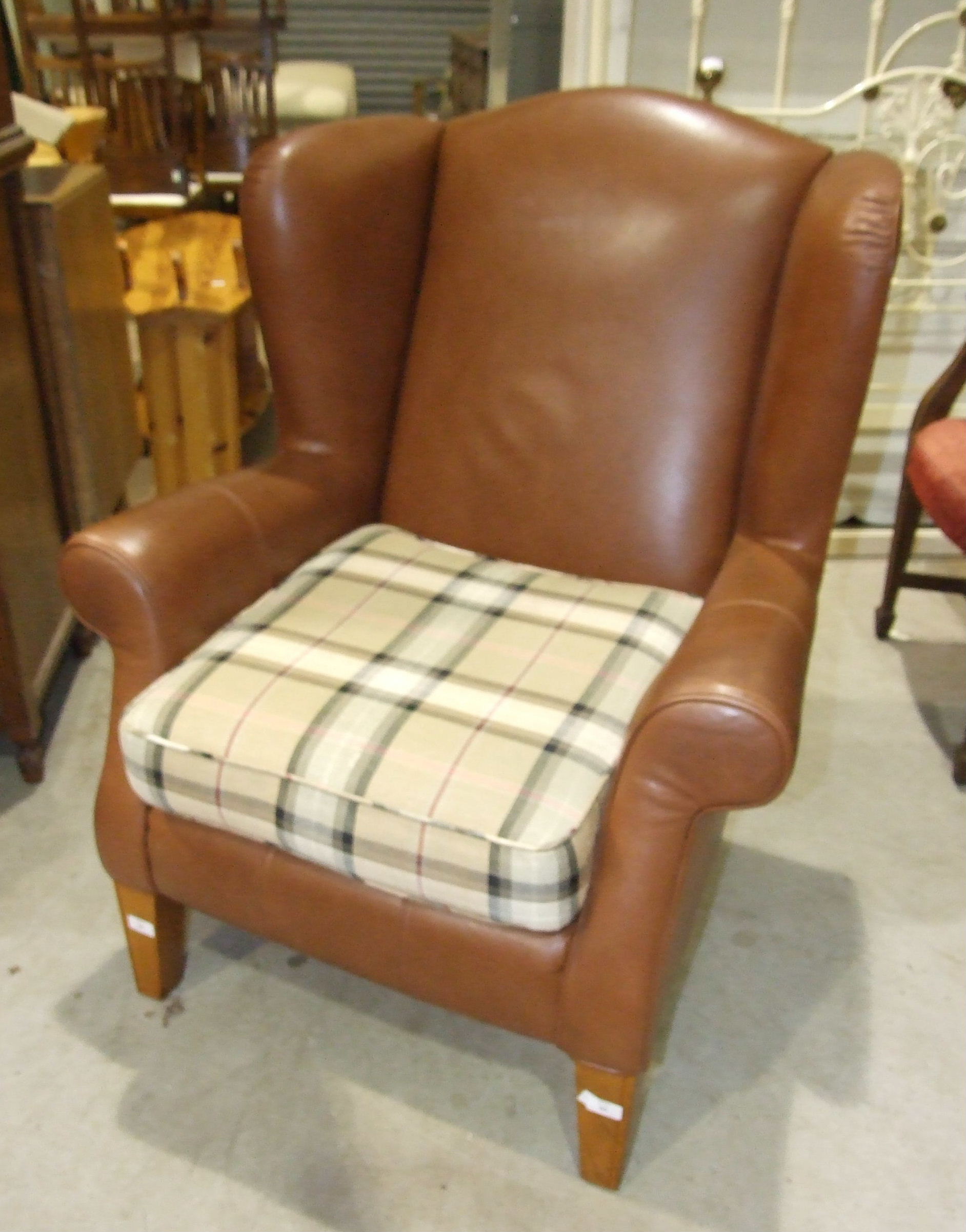 A modern brown "leather" Multi York wing back armchair on tapered wood legs.