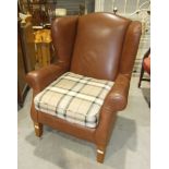 A modern brown "leather" Multi York wing back armchair on tapered wood legs.