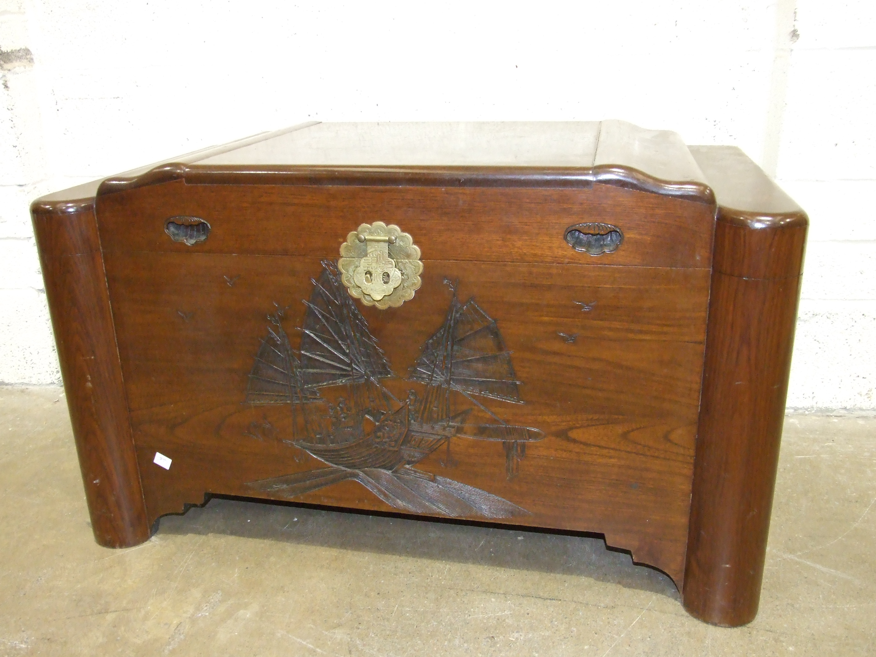 An Oriental hardwood camphor-wood-lined blanket box with carved "junks" decoration on front, 102cm