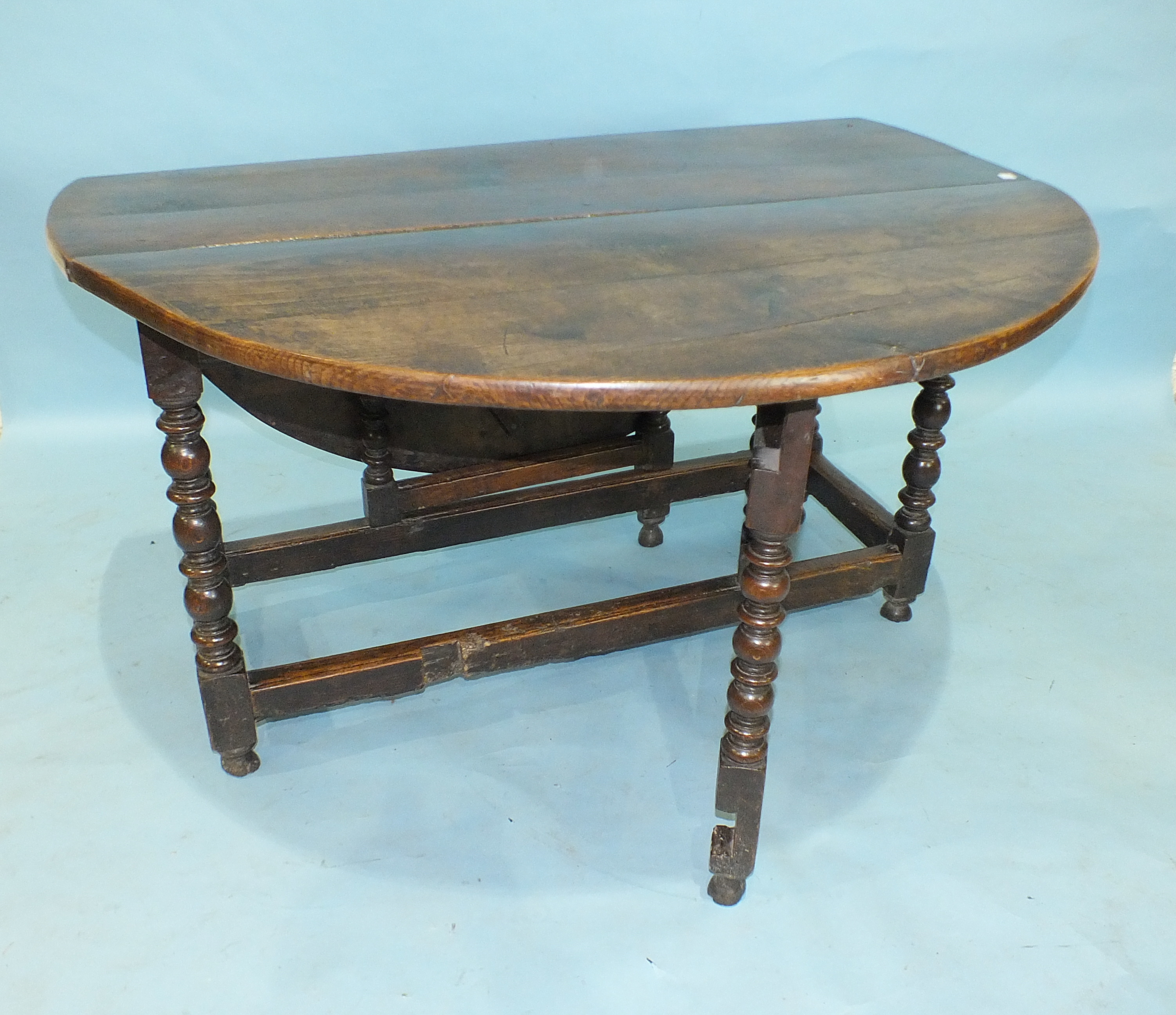 An antique oak drop-leaf dining table, the oval top above an end frieze drawer, raised on bobbin- - Image 2 of 3