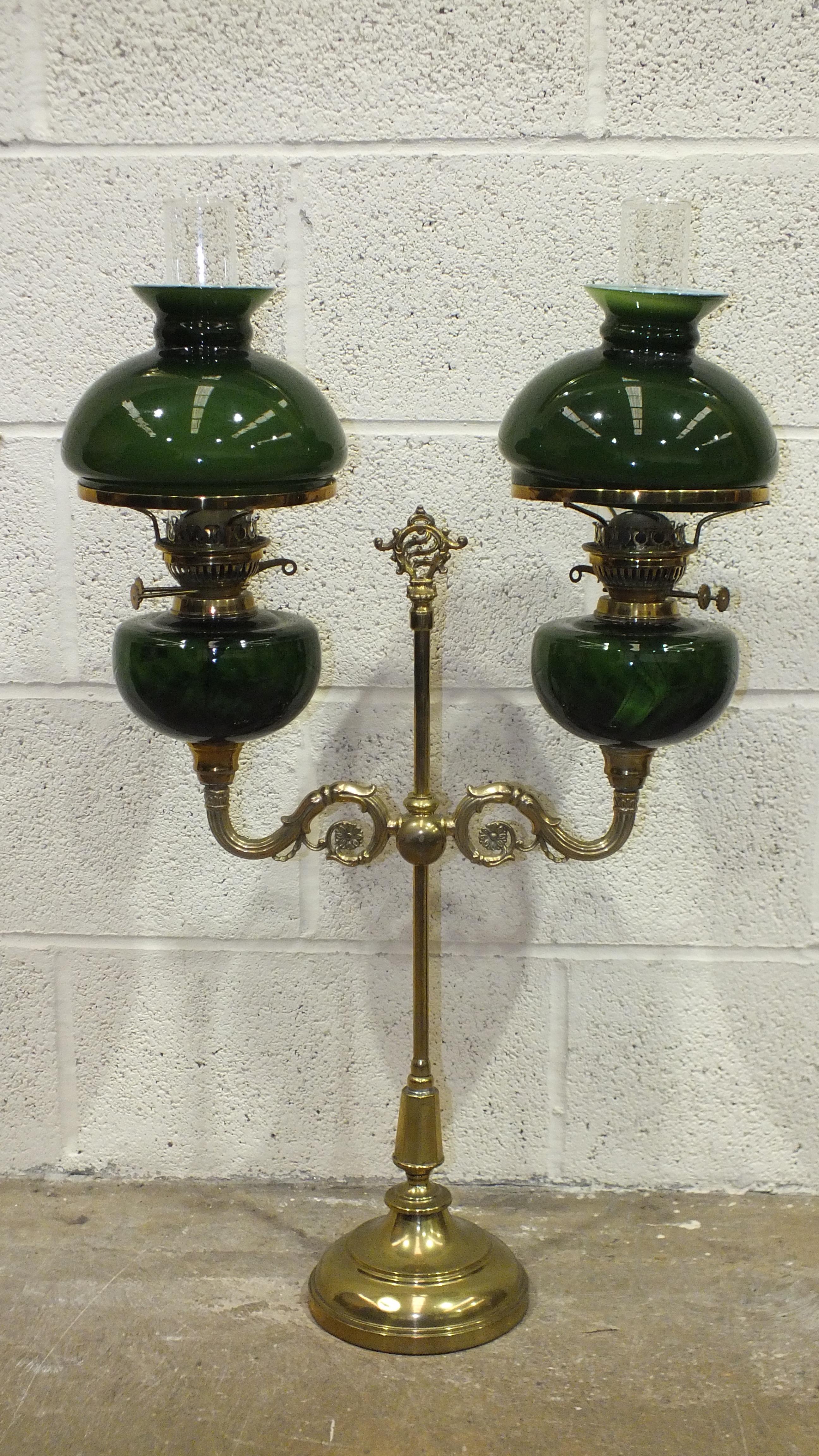 A reproduction student brass double oil lamp with green glass reservoirs and shades, 81cm high
