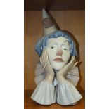 A Lladro bust of a sad clown, head in hands, 31cm high.