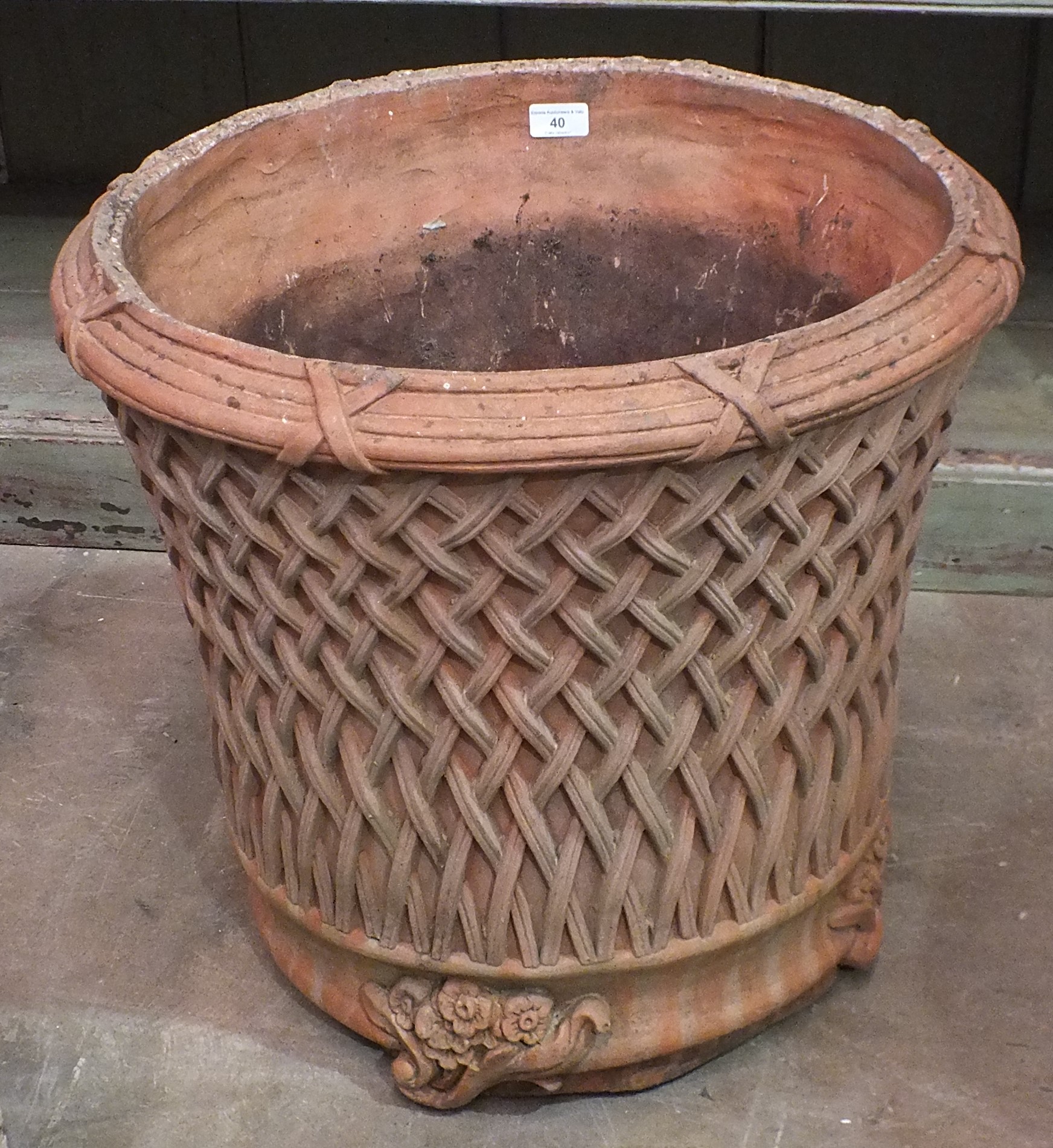 A modern terracotta planter decorated with lattice work, on foliate feet, 52cm high, 54cm diameter.