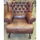 A modern leather upholstered armchair on stained wood claw and ball feet, with button back, (