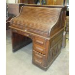 A small oak roll-top desk, the tambour front enclosing an arrangement of pigeon holes and small