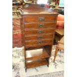 An Edwardian stained wood music cabinet of five drop-down doors above two shelves, 50cm wide,