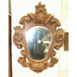 A carved pitch pine foliate mirror with shaped central plate, 58 x 43cm.