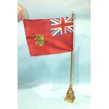 An early-20th century brass conference table flag pole with flag, 62cm high, stamped beneath Eneret?