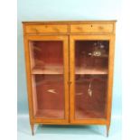 A 19th century satinwood bookcase, having a pair of small drawers above two glazed doors, on