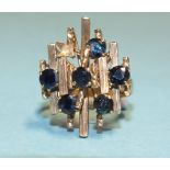 An 18k gold dress ring of abstract form set six round-cut sapphires, (one setting vacant), size P,
