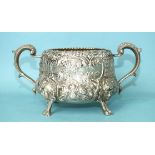 A two-handled sugar basin profusely-decorated and chased with foliage, raised on cast mask feet,