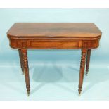 A George IV mahogany fold-over card table, having a concealed frieze drawer on ring-turned legs with