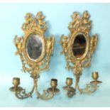 A pair of cast brass and mirrored girandoles decorated with cherubs and ribbon-tied husks, 34cm