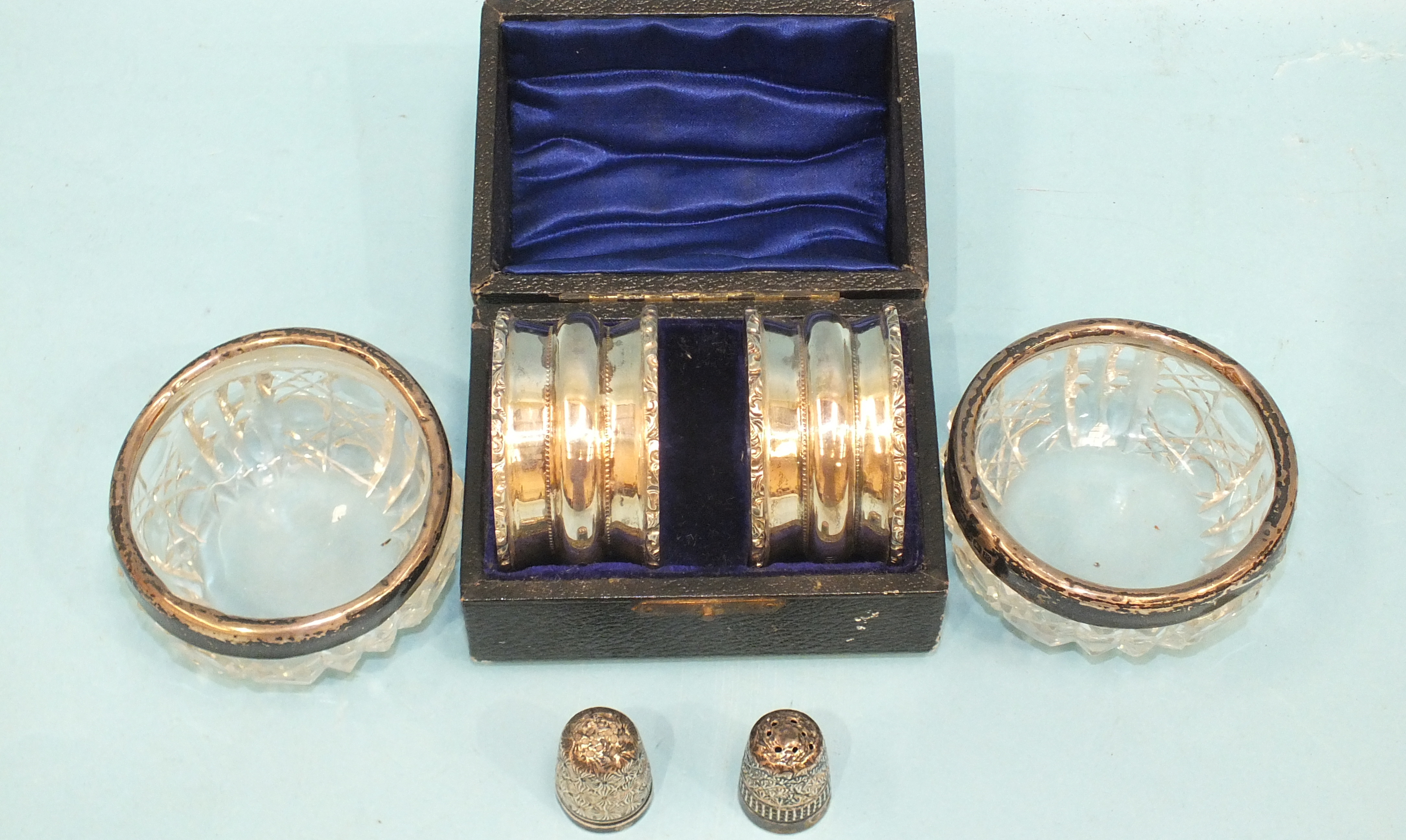 A pair of cased silver napkin rings, Birmingham 1910, a pair of silver-mounted glass salts, a silver