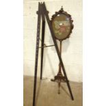 A Victorian walnut pole screen with oval needlework panel, 37 x 47cm, on tripod support 150cm high