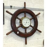 A Sestrel brass bulkhead barometer, 19cm diameter, set within a wooden ship's wheel, 71cm overall.