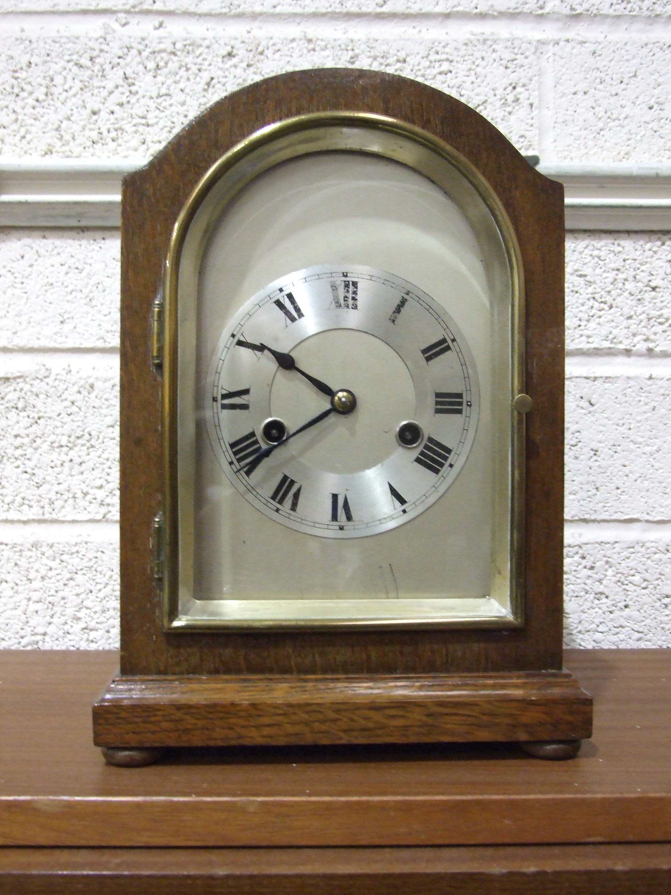 An early-20th century oak-cased arched mantel clock, with silvered dial and gong-striking