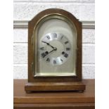 An early-20th century oak-cased arched mantel clock, with silvered dial and gong-striking