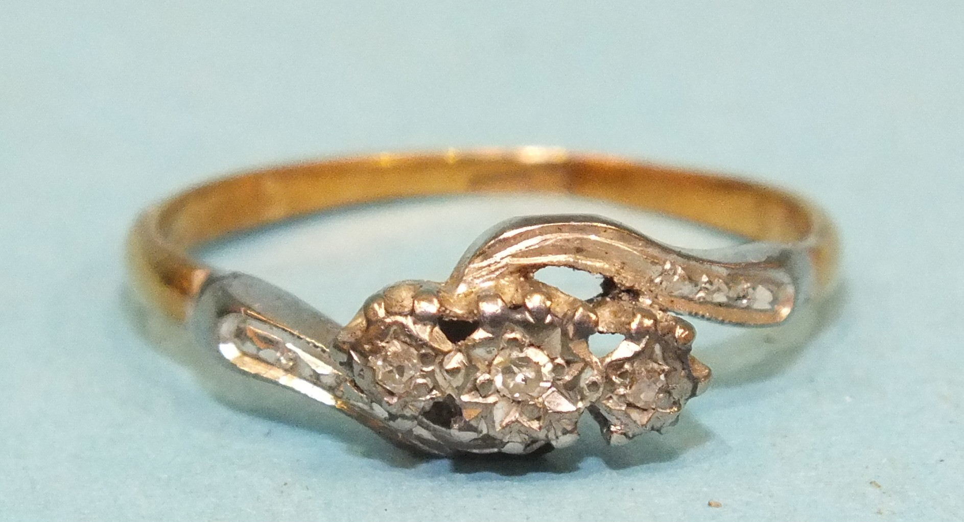 An 18ct yellow and white gold crossover ring set three small 8/8-cut diamonds, size M½, 2.1g.