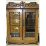 An Edwardian oak cased smokers' cabinet, the pair of glazed doors opening to reveal three drawers