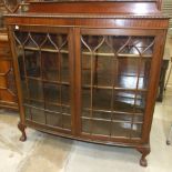 A mahogany display cabinet, the slightly bowed rectangular top above a pair of astragal glazed