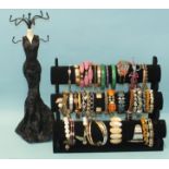 Forty various bracelets and bangles on a display rack and another jewellery display rack.