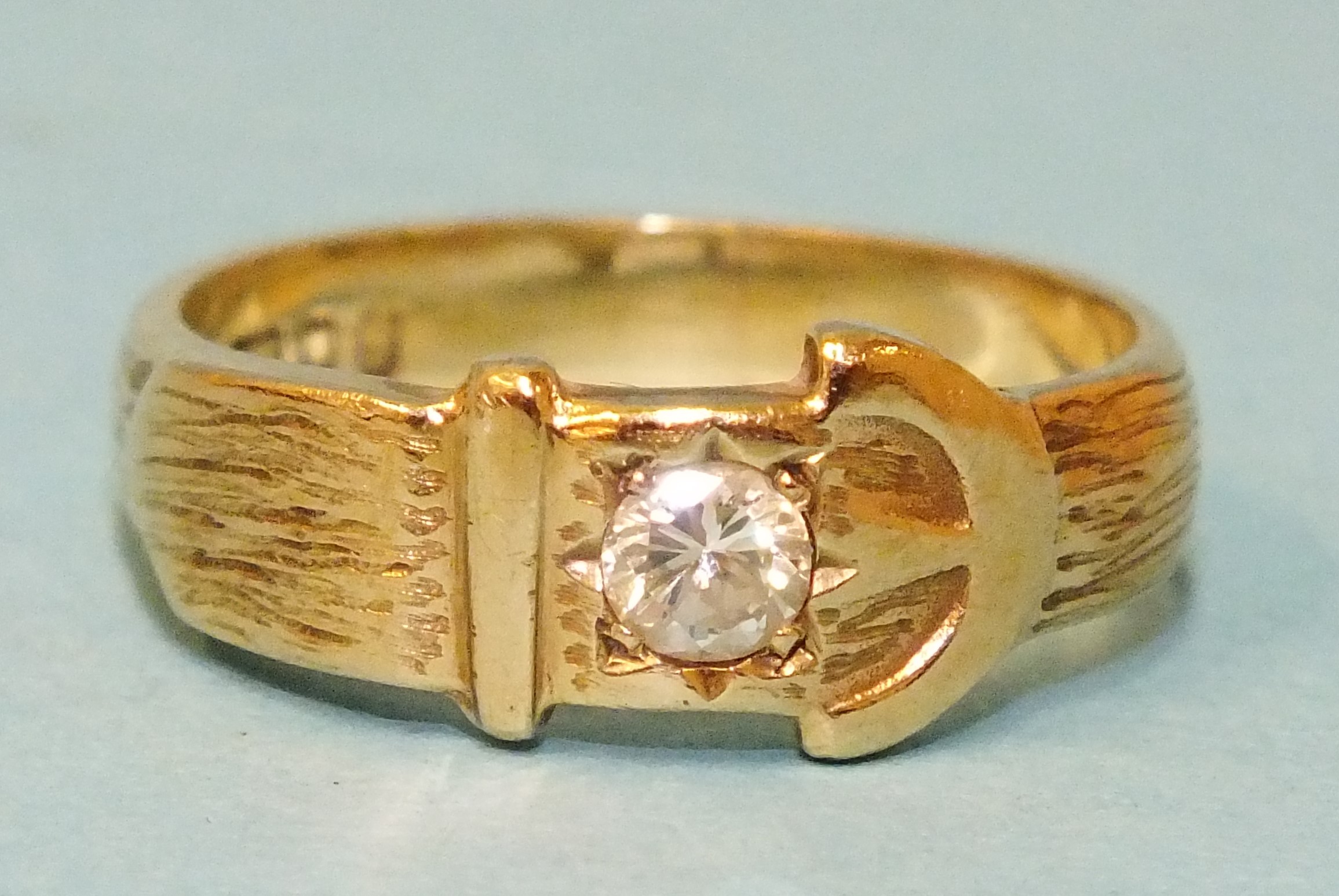 A 9ct gold buckle ring set a brilliant-cut diamond of approximately 0.2cts, size Q, 4.8g.