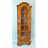 An antique walnut narrow corner cupboard, the arched cornice above one long glazed door and a
